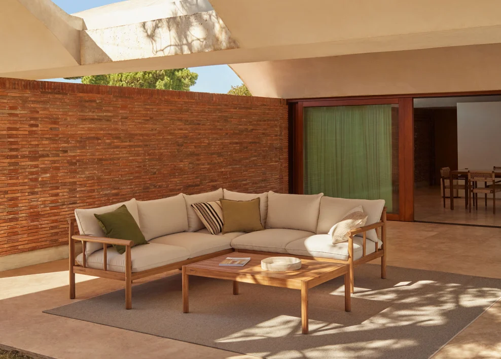 Portico moderno con divano angolare in legno e cuscini neutri, perfetto per un ingresso accogliente e funzionale