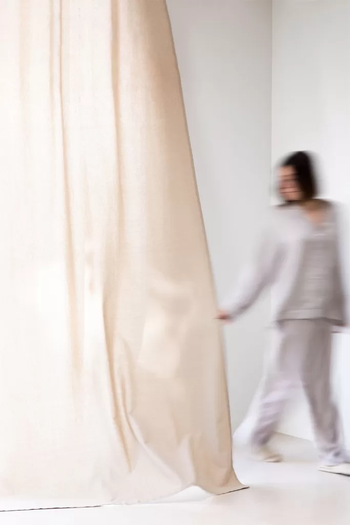 Rideaux légers et voilages habillant les fenêtres d'une chambre verte et grise avec élégance.