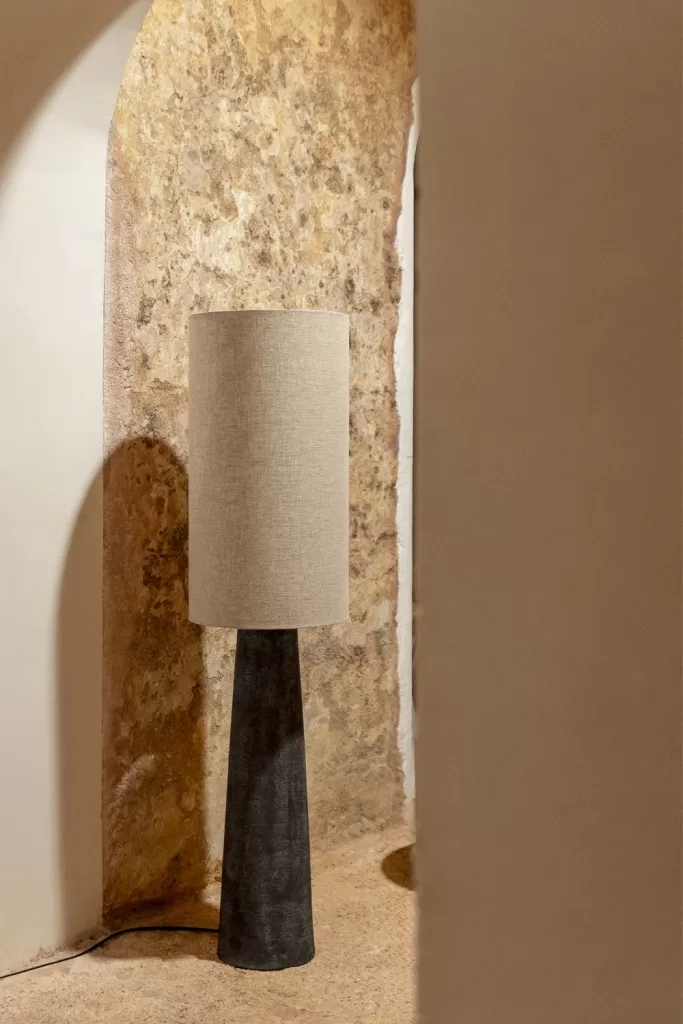 Luminária de chão na sala de estar em cinza e bege, com base preta, criando um contraste elegante na decoração interior.