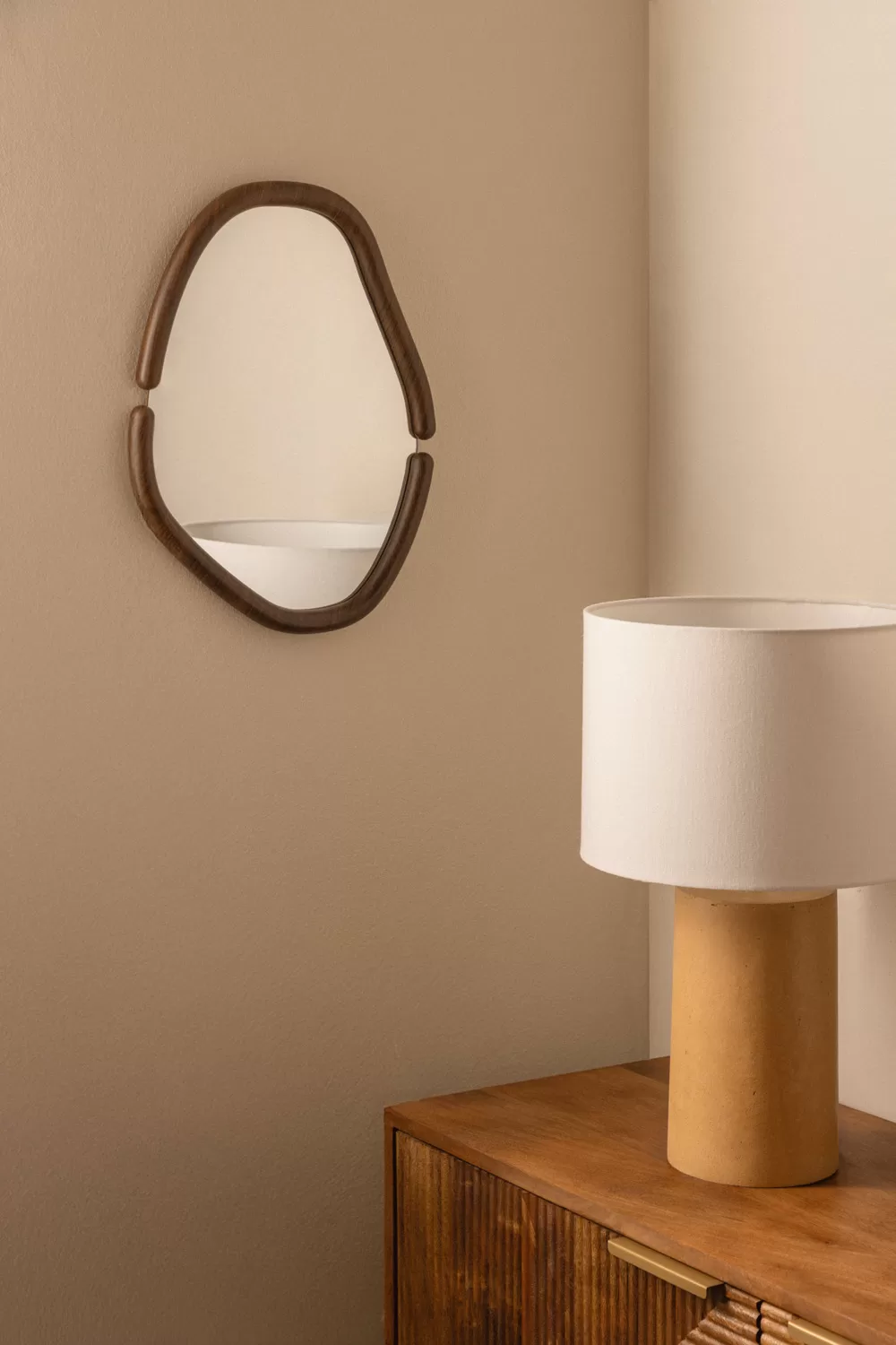 Decorar pared con espejo pequeño de contorno irregular y marco fino. Estilo fluido y contemporáneo para dormitorios o rincones acogedores.