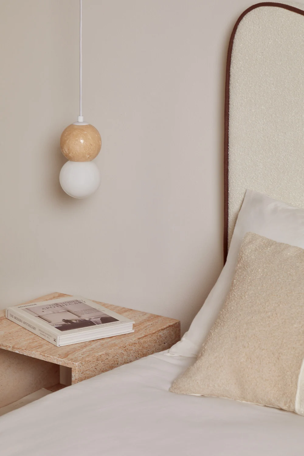Detalle de lámpara colgante y mesita minimalista en tonos neutros para decorar una habitación de matrimonio pequeña con estilo cálido
