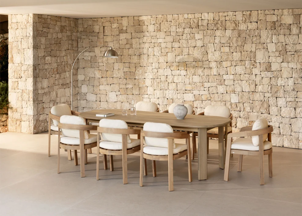 Sala da pranzo su una piccola terrazza chiusa, arredata con mobili in legno chiaro, toni neutri e un muro in pietra, ideale per ampliare visivamente piccoli spazi con uno stile naturale.
