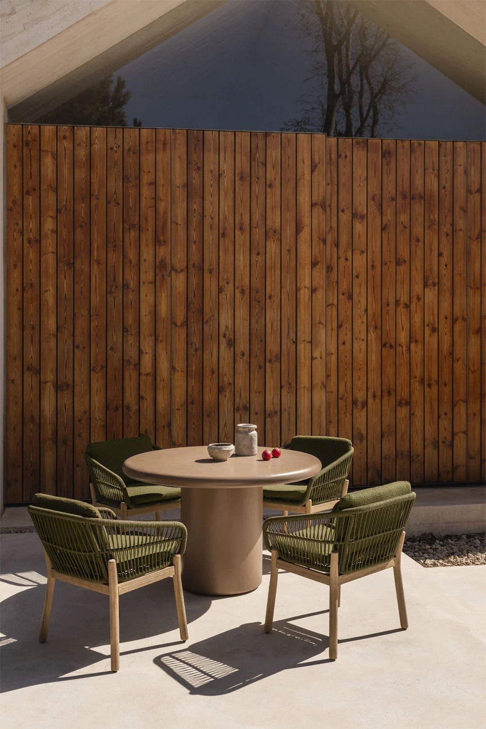 Area pranzo esterna con moderno tavolo rotondo e sedie verdi, un'idea compatta ed elegante per godersi il giardino in coppia o in piccoli gruppi.