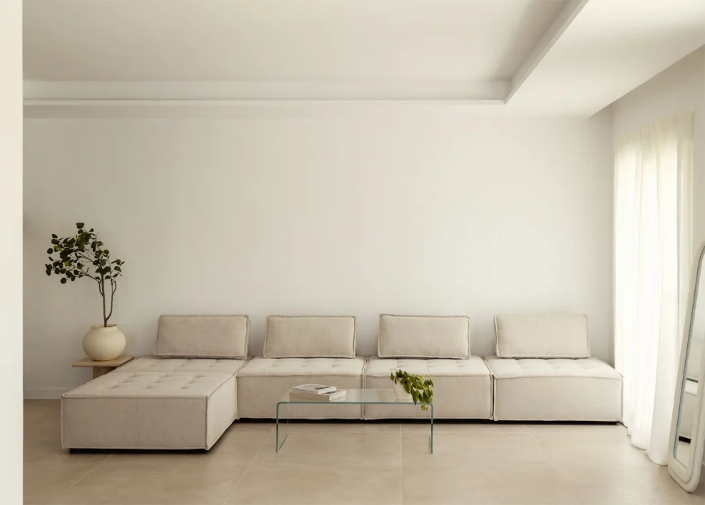 Sofá de tela beige en salón minimalista, ideal para aplicar técnicas de limpieza según el tipo de tejido y etiqueta de mantenimiento