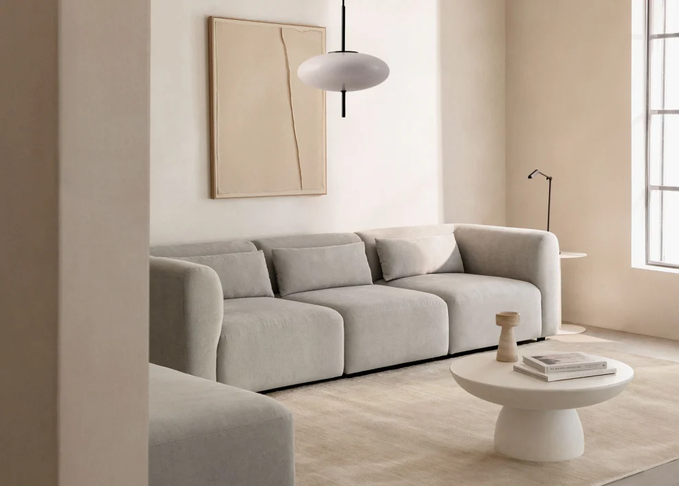 Sofá de tela claro en salón elegante, perfecto para aplicar una limpieza paso a paso con aspirado, vinagre y bicarbonato según el tipo de mancha