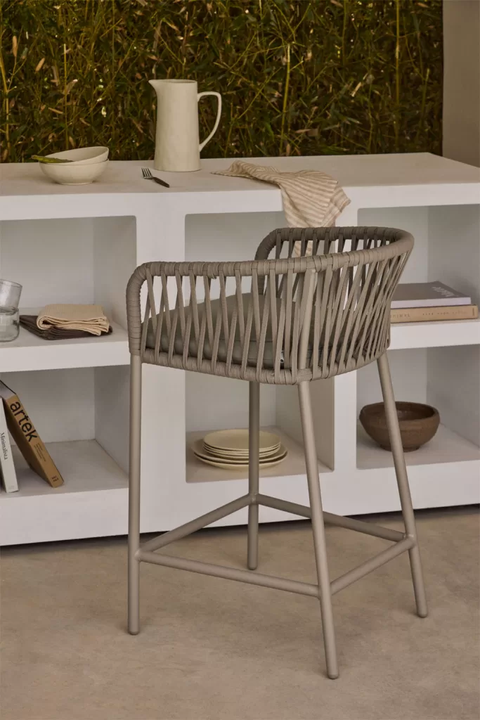 Pequeña barra blanca con taburete para exterior, una idea funcional para terrazas con zona de bebidas o cocina.