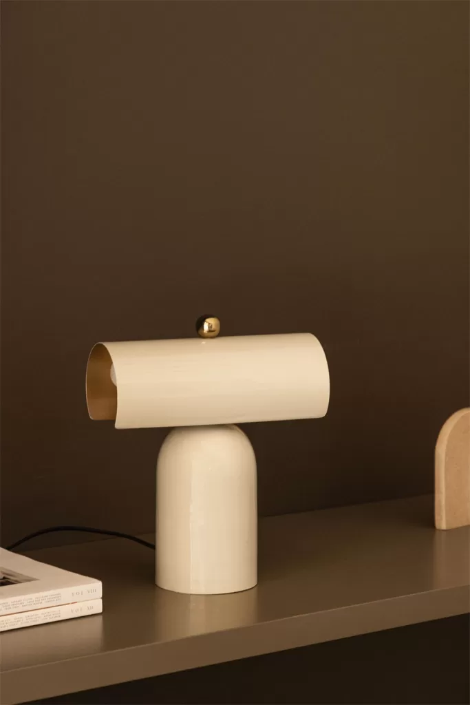 Lampe au design minimaliste sur une table d'appoint, idéale pour décorer une chambre principale moderne avec un style élégant et fonctionnel.