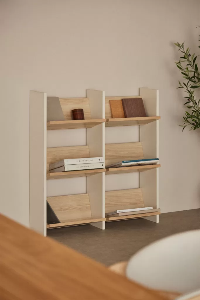 Étagères blanches et en bois avec des livres et des échantillons de couleurs disposés dans des tons coordonnés pour une décoration d'étagère avec un récit de couleurs