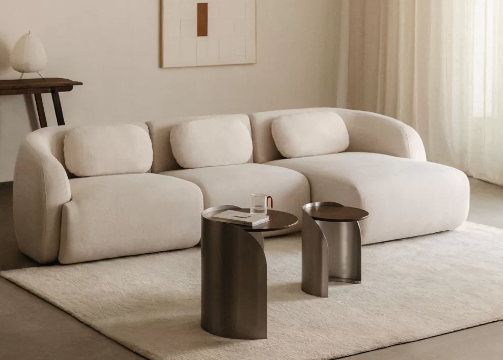 Ein helles modulares Sofa mit Satztischen auf einem neutralen Teppich, ein Beispiel für eine clevere Raumaufteilung zur Dekoration einer kleinen Wohnung mit klar abgegrenzten Bereichen.
