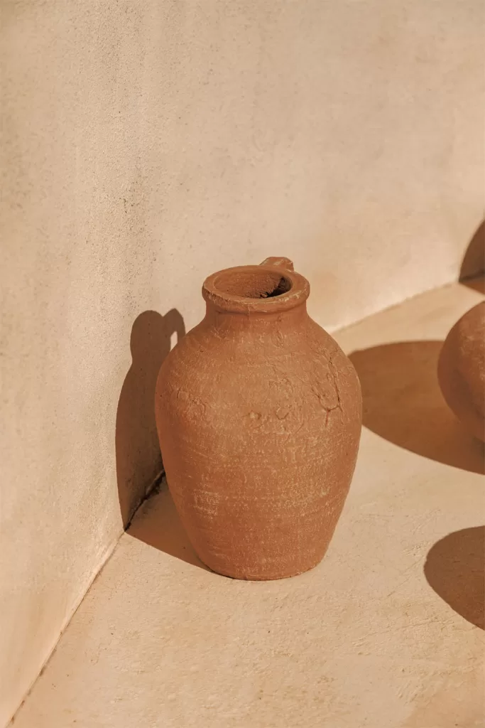 Decoração de sala de estar em cinza e bege com um vaso de terracota como um toque de cor estratégico e elegante.