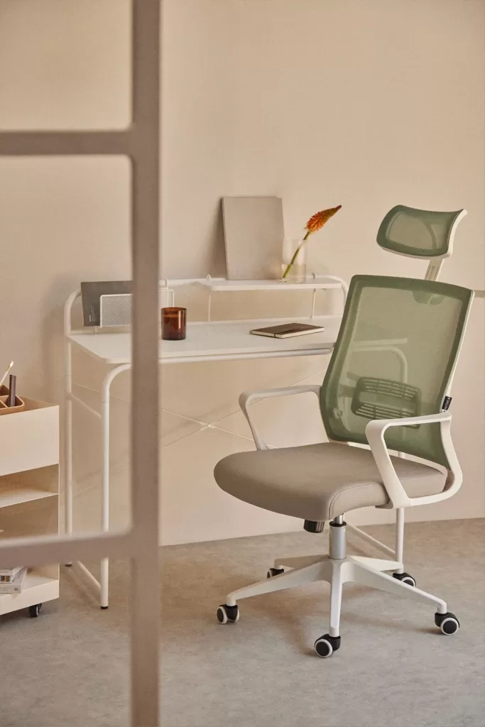 Mesa branca minimalista com cadeira ergonómica verde para área de estudo em decoração moderna de quarto de adolescente.