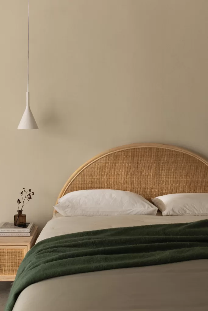 Kopfteil aus Rattan an einem Doppelbett, das einen visuellen Fokus schafft, ohne ein kleines Schlafzimmer für Paare mit Kleiderschrank zu überladen