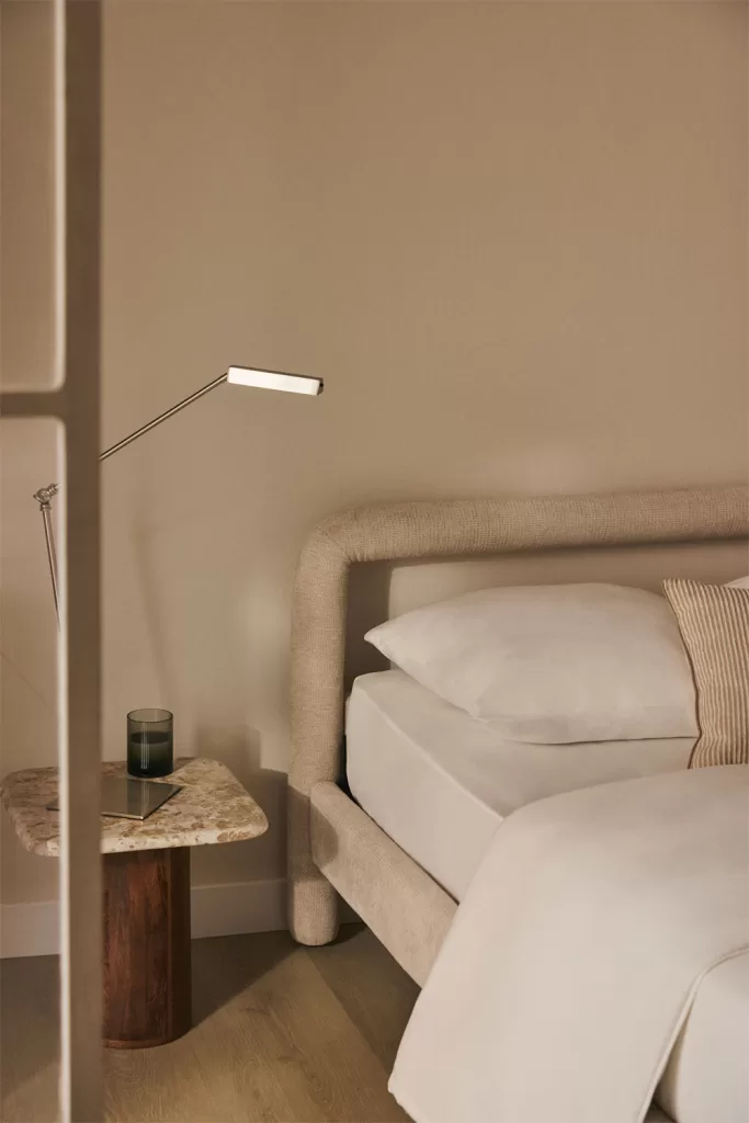 Cama con paredes en tonos grises suaves y textiles blancos en un dormitorio gris y blanco acogedor