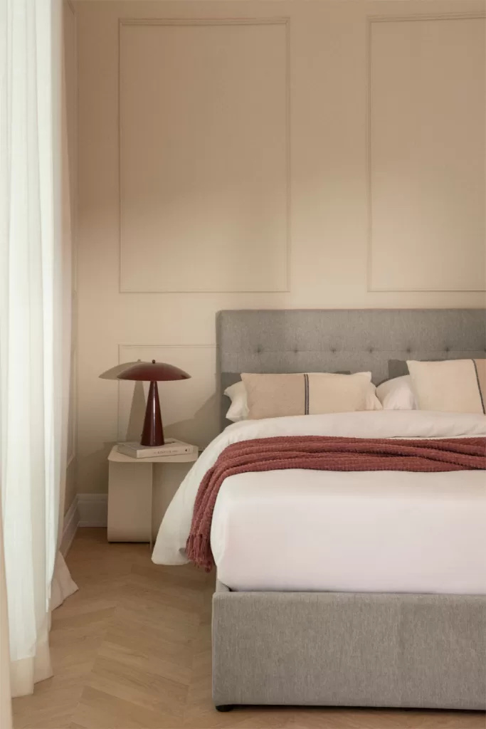 Lit rembourré gris servant de base neutre pour la décoration d'une chambre verte et grise