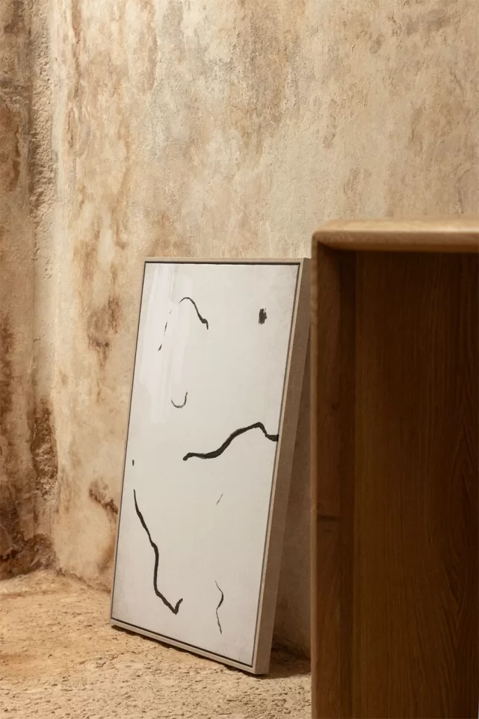 Cuadro decorativo apoyado en la pared como acento artístico en dormitorio gris y blanco