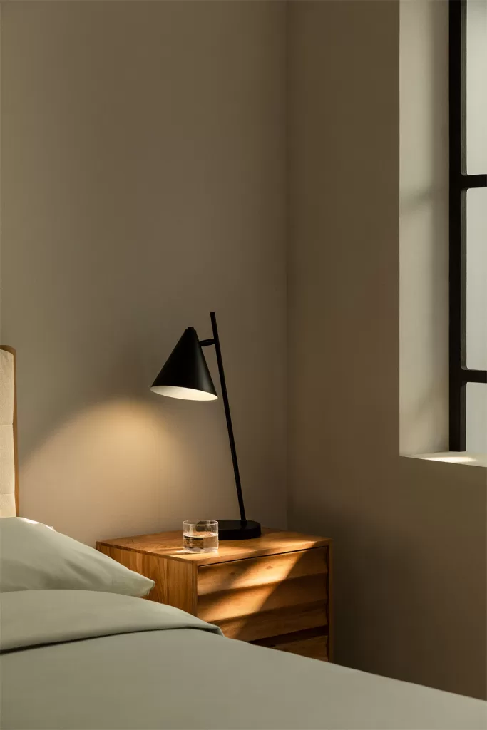 Applique et lampe de table sur une table en bois illuminant une chambre grise et bois avec une ambiance chaleureuse