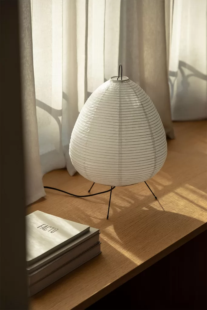 Lámpara de mesa con detalles metálicos sobre superficie de madera en dormitorio gris y blanco elegante