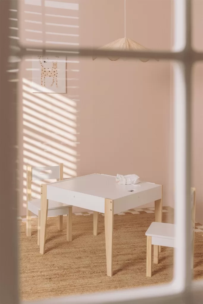 Décoration de chambre de bébé dans des tons neutres avec une table et des chaises pour enfants en bois
