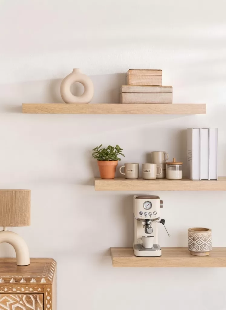 Estantes flotantes de madera con decoración neutra, cafetera y tazas para decorar un rincón para el café en pared