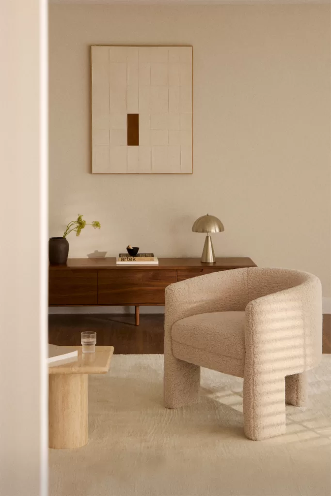 Fauteuil beige et buffet en bois au décor minimaliste gris et bois ; la pièce maîtresse