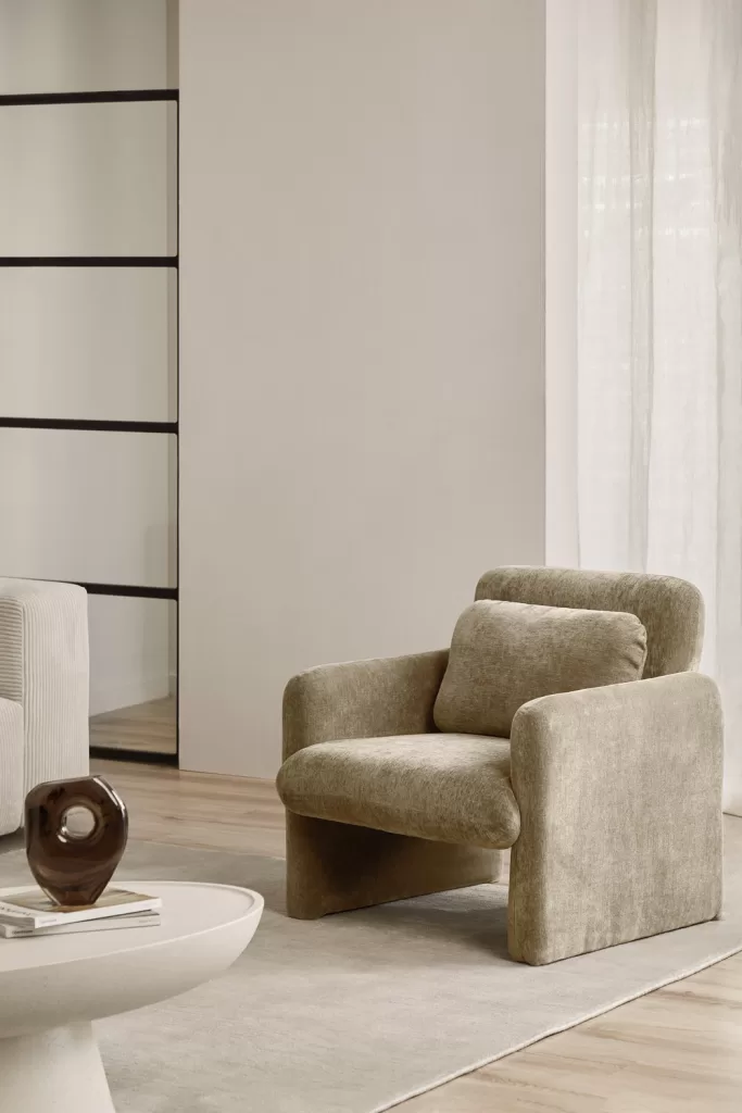 Sillón de acento en tonos neutros como pieza destacada en un dormitorio gris y blanco contemporáneo