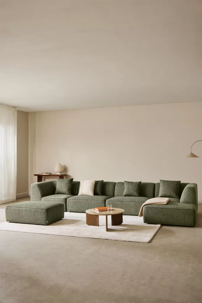 So kombinieren Sie ein grünes Sofa mit Kissen in verschiedenen Grüntönen und einem hellen Teppich in einem monochromen Wohnzimmer