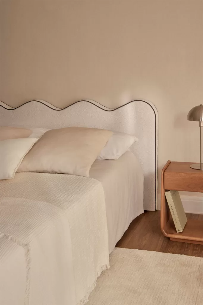 Mur de tête de lit dans une chambre parentale, décoré d'une tête de lit capitonnée et d'une table de chevet moderne.