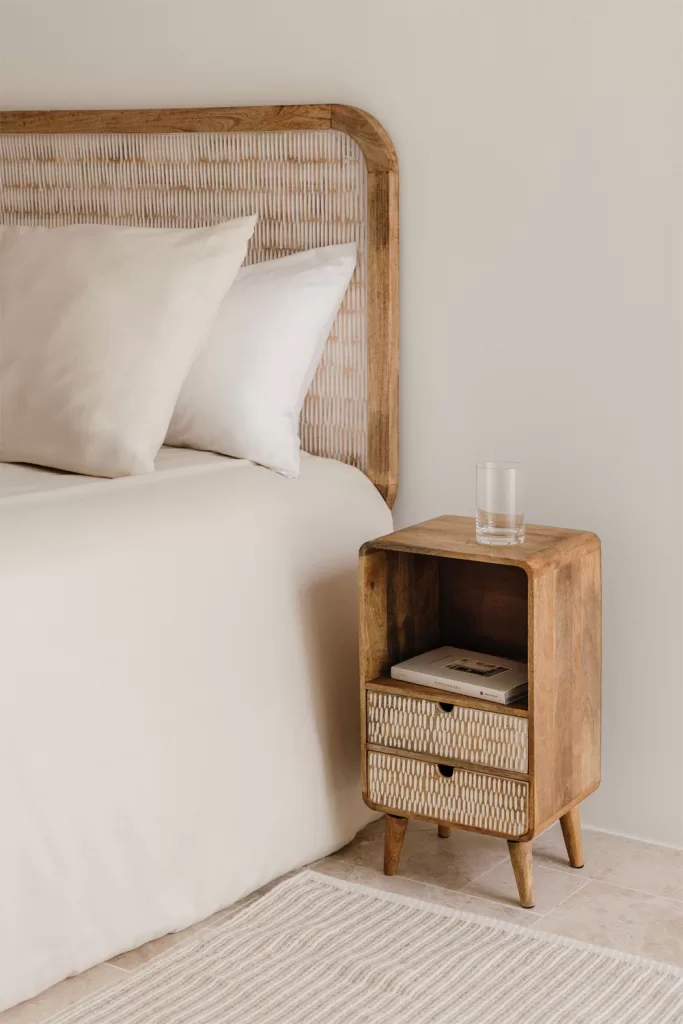 Décoration asymétrique du mur de la tête de lit dans une chambre parentale, avec une table en bois et une lampe en verre.
