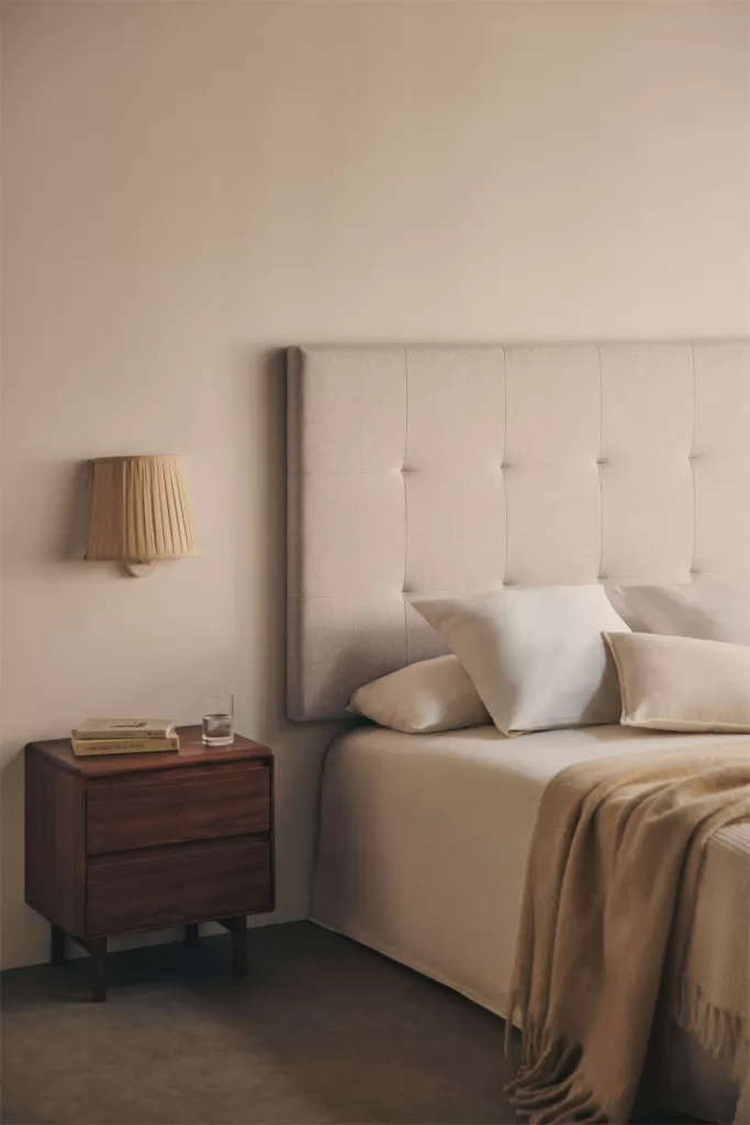 Appliques murales design installées de part et d'autre d'une tête de lit capitonnée, pour un éclairage de style hôtelier dans une chambre parentale.
