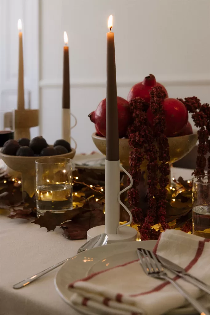 Mesa com arranjo de velas, pinhas e uma grinalda dourada, criando um ponto focal acolhedor numa decoração de Natal para sala pequena.