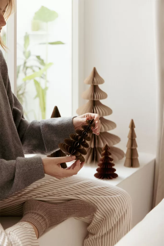 Árvores de Natal de papel em favo de mel de diferentes tamanhos, como alternativa sustentável e minimalista à árvore tradicional.