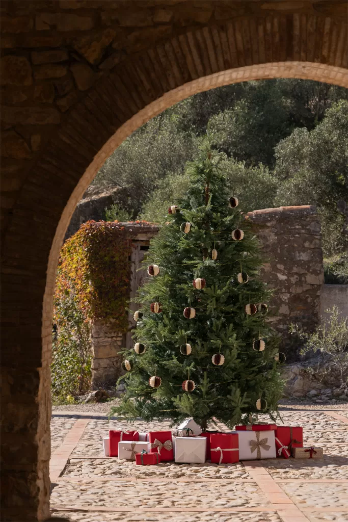 Árvore de Natal minimalista com ramos espaçados e poucos enfeites, seguindo a tendência de design natural e simples.