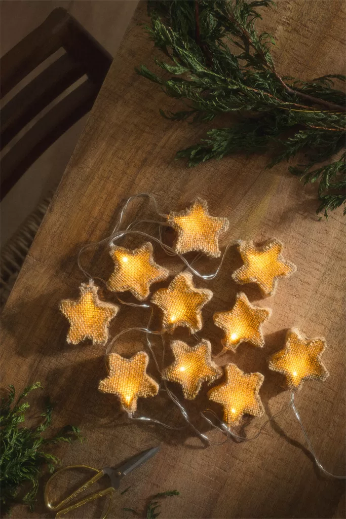 Guirlande décorative LED Doram en forme d'étoiles posée sur des branches de sapin, idée lumineuse pour la décoration de Noël.