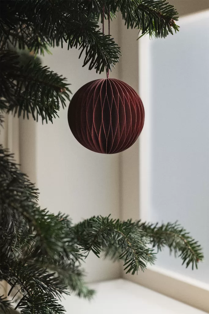 Sapin décoré avec un ensemble de boules de Noël en papier nid d'abeille Elsa et des ornements argentés pour un effet texturé.