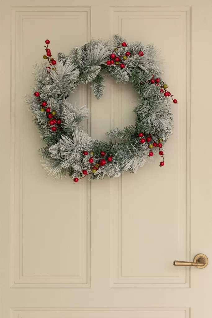 Weihnachtskranz aus Winterlaub und roten Beeren über dem Kamin als strukturgebender Blickfang.