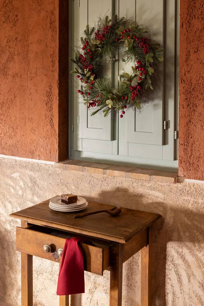 Décoration de fenêtre de Noël avec une couronne naturelle sur des volets extérieurs de style classique