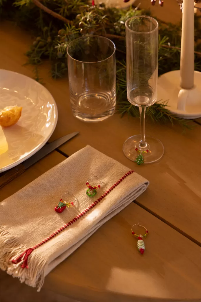 Détails décoratifs de Noël sur les serviettes et marque-verres pour compléter un centre de table de Noël élégant.