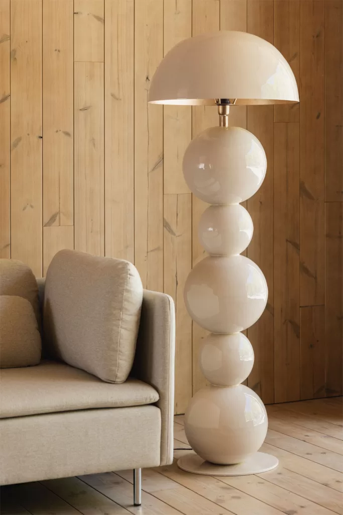 Lámpara de pie escultural blanca junto a sofá beige en rincón cálido de madera para iluminación de Estilo minimalista