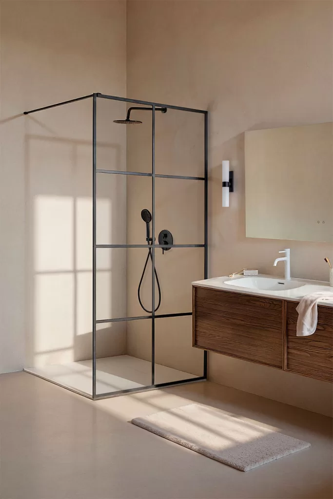Paroi de douche fixe en verre transparent avec profilés noirs, installée dans une salle de bains moderne au style minimaliste.