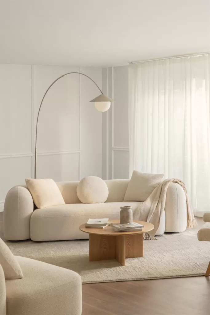 Salón de Estilo minimalista con sofá crema, alfombra de yute y mesa de madera clara para aportar calidez con texturas