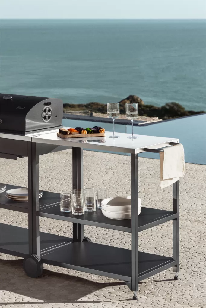 Mobiler Küchenwagen aus grauem Metall auf einer Terrasse mit Meerblick