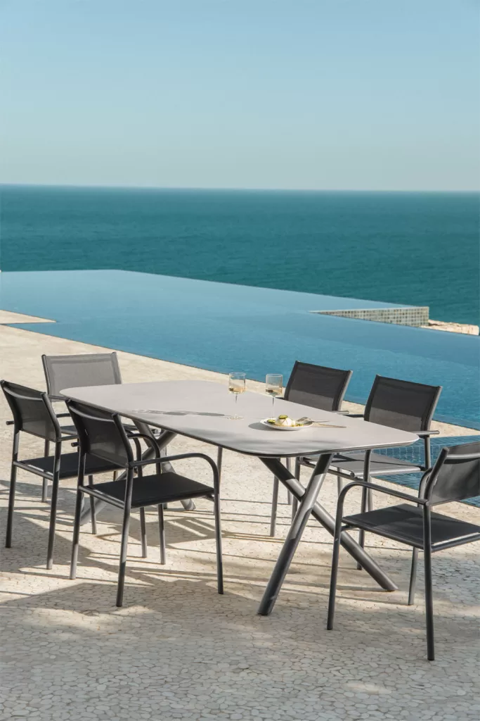 Mesa y sillas de exterior junto al mar en porche con cocina exterior integrado y estilo contemporáneo
