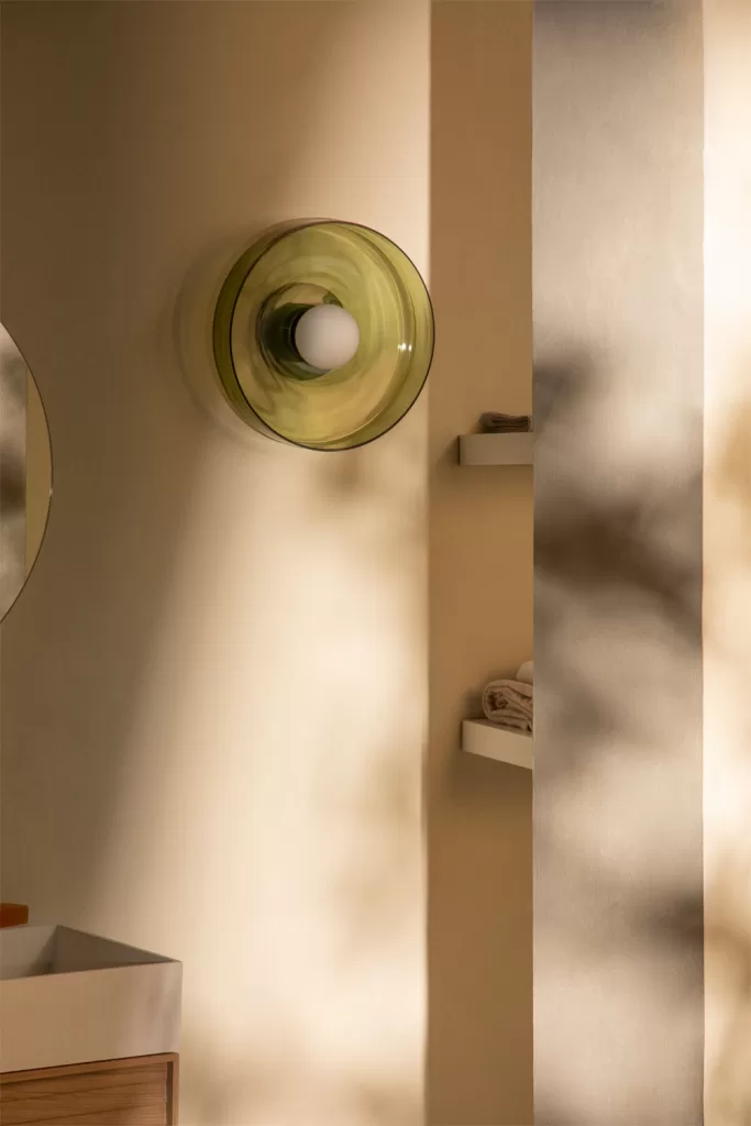 Aplique de pared en vidrio verde para organizar lavadero muy pequeño con iluminación ambiental cálida y de diseño.