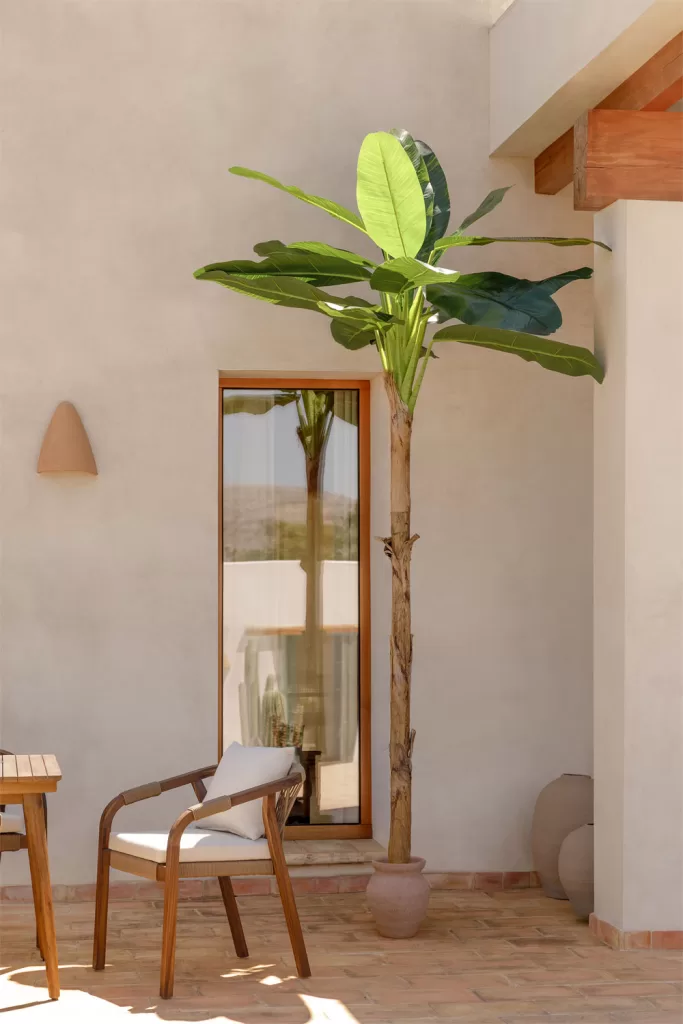 Patios interiores con encanto con planta artificial tipo bananero, sillas de madera y suelo de terracota