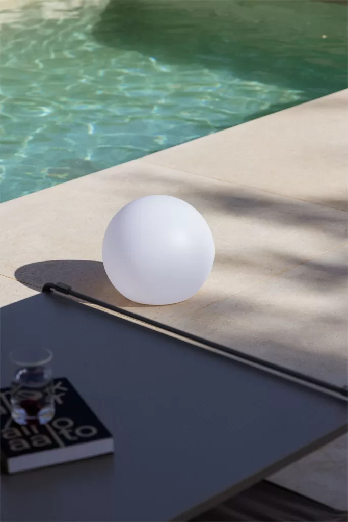 Jardines con piscina con lámpara esférica exterior junto al agua e iluminación ambiental nocturna