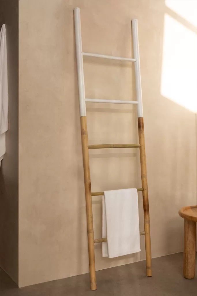 Escalera decorativa de bambú y madera blanca para organizar lavadero muy pequeño colgando toallas y perchas ligeras.