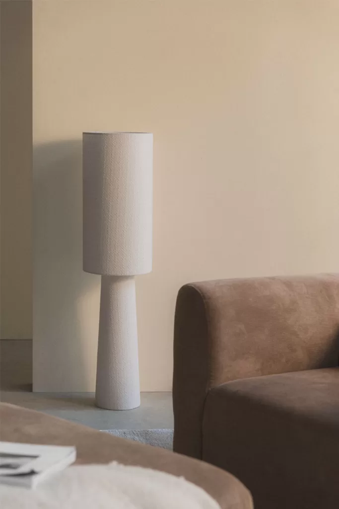 Patios interiores con encanto con lámpara de pie y sofá marrón, iluminación cálida en rincón acogedor