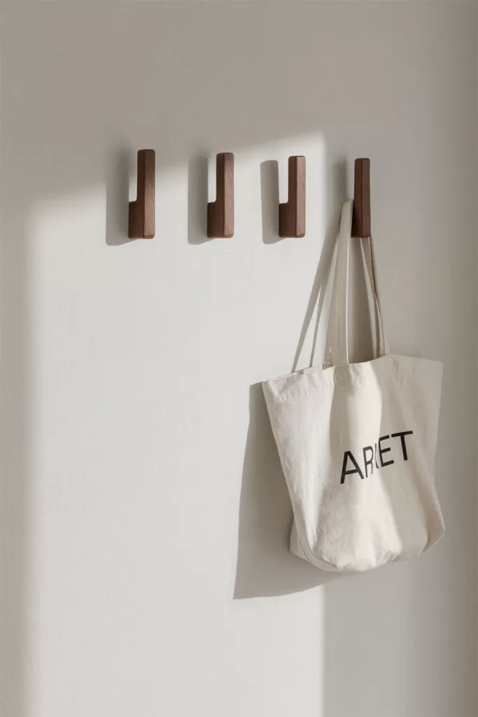 Percheros de pared en madera oscura para organizar lavadero muy pequeño aprovechando el espacio mural con ganchos.