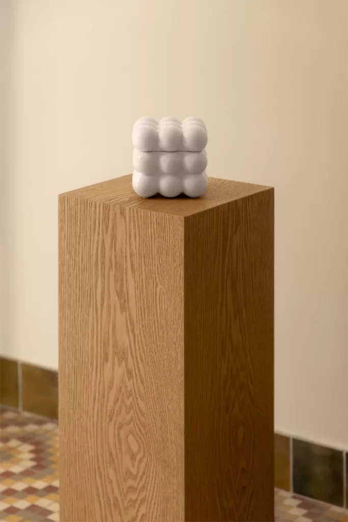 Caja decorativa blanca sobre pedestal de madera, opción de como decorar una vitrina de cristal con orden visual