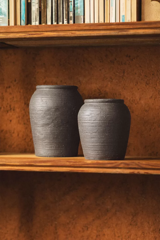 Jarrones cerámicos negros en balda de madera, idea de como decorar una vitrina de cristal con altura y profundidad